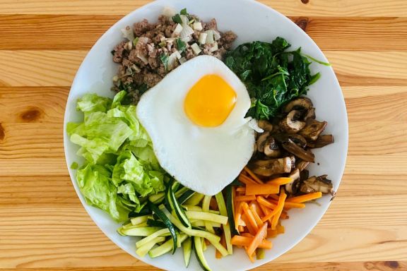 Traditional Korean bibimbap served at a homestay with Lexis Korea. A bowl dish featuring a harmonious mix of various vegetables, meat, and a fried egg.